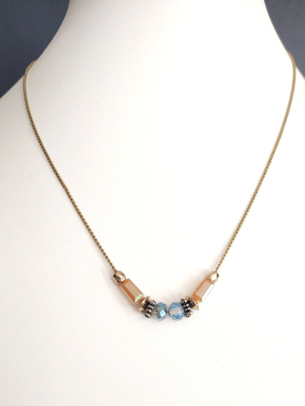 Delicate gold necklace with iridescent orange, white and blue beads